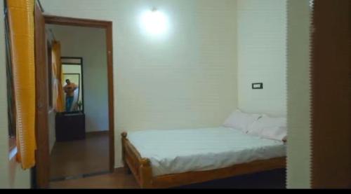 a small bedroom with a bed and a mirror at Alekadu hill view homestay in Mudigere