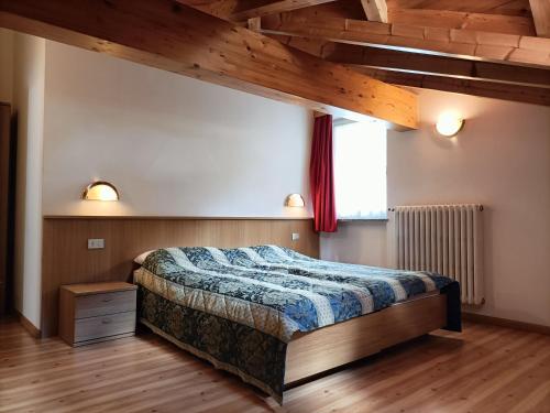 een slaapkamer met een bed en een houten vloer bij Appartamenti Villa Maria in Canazei