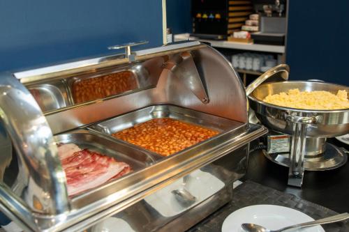 a buffet line with meat and other food items at Travelodge Málaga Airport in Málaga
