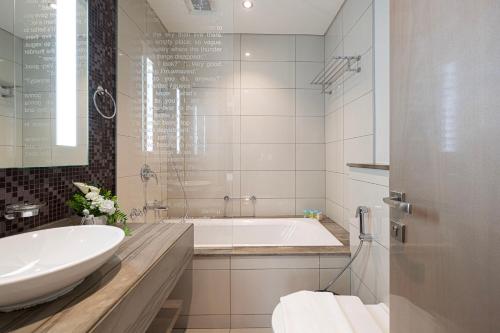 a white bathroom with a tub and a sink at Luxurious 2BDR Apartment in Paramount Towers with Burj Khalifa Views in Dubai
