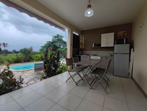 a kitchen with a table and chairs and a pool at Fleur de canne in Sainte-Rose