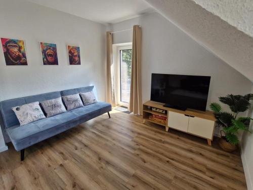 a living room with a blue couch and a flat screen tv at NEU! FeWo AllerGrün, Balkon mit Blick in die Natur in Borstel