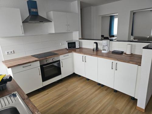 a kitchen with white cabinets and a wooden floor at Monteurs- & Gästewohnungen nähe Raffinerie Leuna & Geiseltalsee für 4Personen in Frankleben