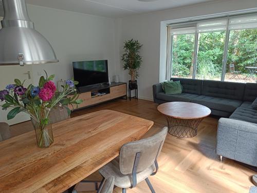 a living room with a couch and a table with flowers at Bosvilla Lochem - Luxe en privacy in de natuur in Lochem
