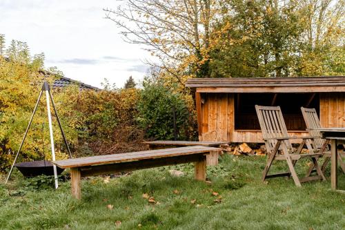 a bench and two chairs next to a cabin at Cooking Over Fire And Coziness Near Ajstrup Beach in Ajstrup Strand