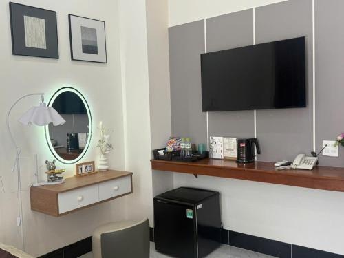 a hotel room with a flat screen tv and a desk at Lucasta Hotel in Can Tho