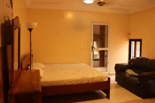 a bedroom with a bed and a couch at Londoninnn in Bijilo