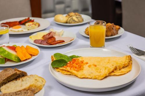 a table with plates of breakfast foods and orange juice at Hotel Central in Nyíregyháza