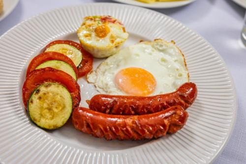 a plate of breakfast food with sausage egg and bread at Hotel Central in Nyíregyháza
