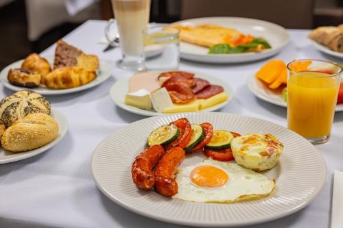 a table with plates of breakfast foods and drinks at Hotel Central in Nyíregyháza