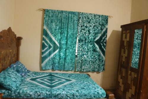 a bedroom with a bed and a green blanket at Londoninnn in Bijilo