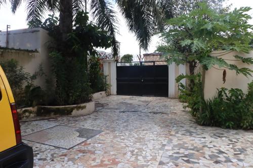 a driveway with a black garage door with a palm tree at Londoninnn in Bijilo