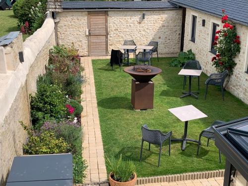 an outdoor patio with tables and chairs on the grass at JunoGîte - Résidence in Bernières-sur-Mer