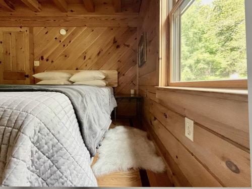 a bed in a wooden room with a window at Red Tail Ridge in North Branch