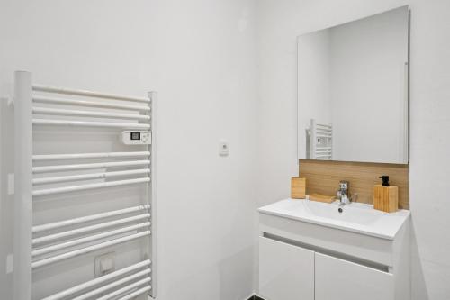 Un baño blanco con lavabo y espejo. en " La Casa verde " Superbe T3, chic & cosy avec climatisation en hypercentre, en Villeurbanne