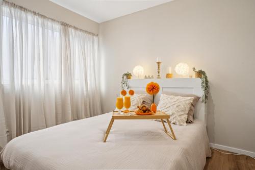 Un dormitorio blanco con una cama con una mesa con naranjas. en " La Casa verde " Superbe T3, chic & cosy avec climatisation en hypercentre, en Villeurbanne