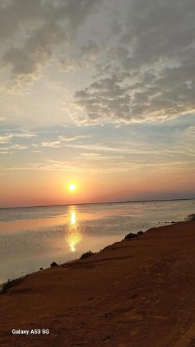 a sunset on the beach with the sun in the water at Villa Dar Rayan & Naelle in Midoun