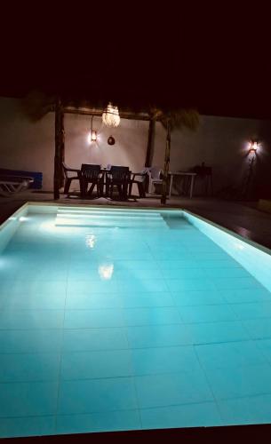 a swimming pool at night with a table and chairs at Villa Dar Rayan & Naelle in Midoun