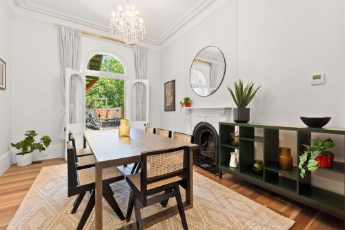 a dining room with a table and chairs and a fireplace at Elegant 6-Bed Home with Harbour Views in Sydney