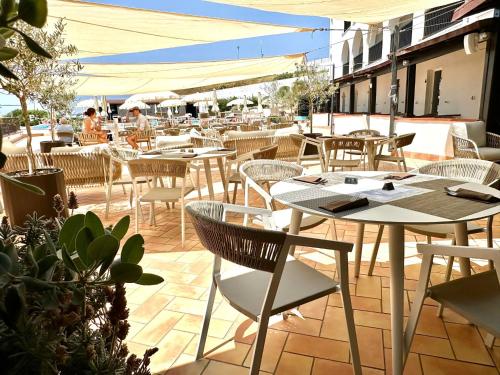an outdoor restaurant with tables and chairs and people in the background at Hotel Calabona in Alghero