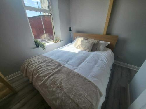 a bedroom with a bed with white sheets and a window at Top Location - Newly Refurbed 2BD Sleeps 6 W Loft in Cork