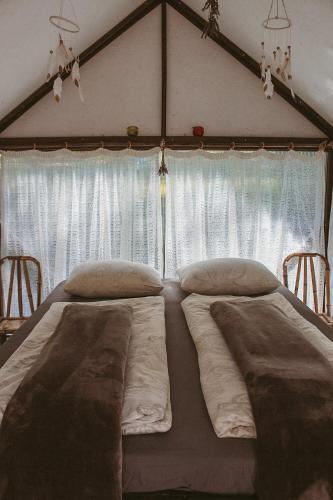 a bedroom with two beds in front of a window at Camping Zanzibāra in Ķekava