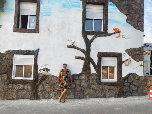 a woman standing in front of a building with a tree painted on it at Casa amazonia PT - Dois amigos in Cernache