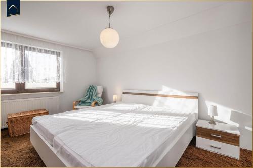 a white bedroom with a large bed and a window at Ferienwohnung zum Koi II DG in Zirchow