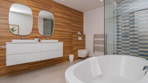 a bathroom with a white tub and two mirrors at Le Paradis 5 in Hermanus