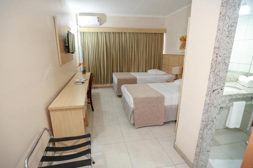 a hotel room with two beds and a desk at Hotel Nacional Inn São Carlos & Convenções in São Carlos