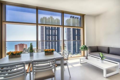 a living room with a table and chairs and a large window at Intempo by Holuxe - 034 - 3rd floor in Benidorm
