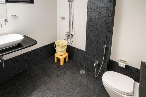 a bathroom with a toilet and a yellow stool at Hotel Avon International in Aurangabad