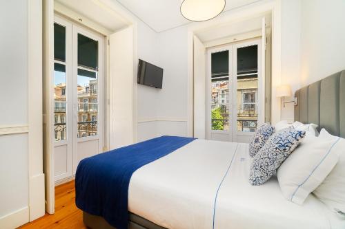 a white bedroom with a large bed and windows at Villa Baixa - Lisbon Luxury Apartments in Lisbon