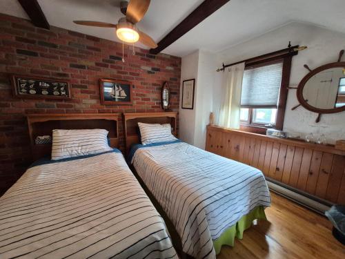 two beds in a room with a brick wall at Refuge du Poète in Longueuil