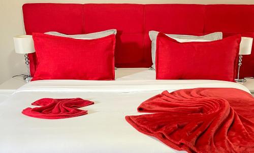 a white bed with red pillows and red blankets at Hotel Ukhay 