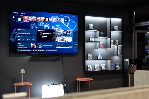a large flat screen tv on a wall with stools at Luna Self Check-in Hotel Klaipeda in Klaipėda