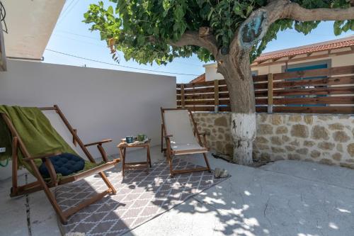 two chairs and a table next to a tree at Anamniseis Giorgio Falasarna in Plátanos