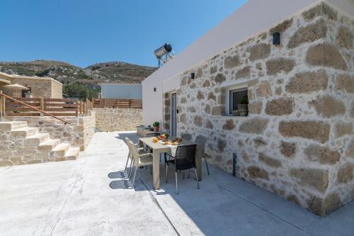 a patio with a table and chairs next to a stone building at Anamniseis Giorgio Falasarna in Plátanos