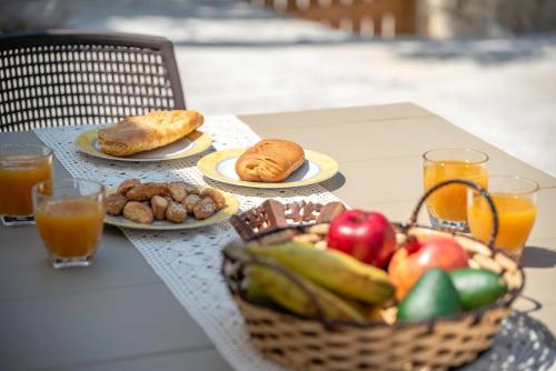a table with plates of food and a basket of fruit at Anamniseis Giorgio Falasarna in Plátanos