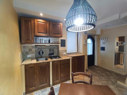 a kitchen with wooden cabinets and a table and a chandelier at Casa Vacanze Porta di Valle in Bagnoregio