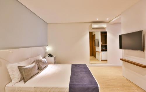 a bedroom with a bed and a flat screen tv at Quality Hotel Blumenau in Blumenau