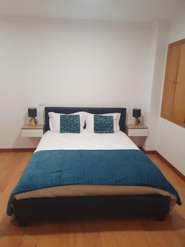 a bedroom with a large bed with a blue blanket at O AL da Baixa in Figueira da Foz