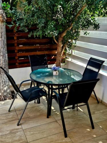 a glass table with chairs and a tree on a patio at Studio in the heart of Paphos in Paphos