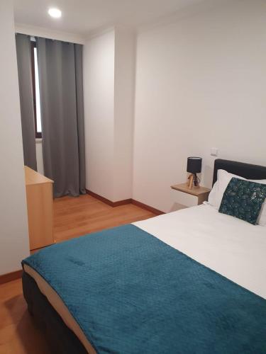 a bedroom with a large bed with a blue blanket at O AL da Baixa in Figueira da Foz
