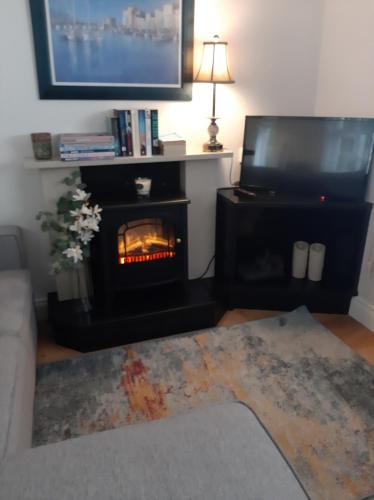 a living room with a fireplace and a tv at Marys Coastal Retreat in Miltown Malbay