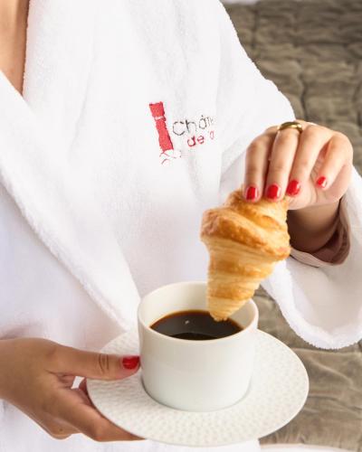 a woman holding a cup of coffee and a piece of bread at Le Château de la Tour in Gouvieux