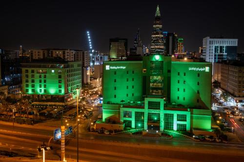 a building with green lights in a city at night at Holiday Inn Olaya by IHG in Riyadh