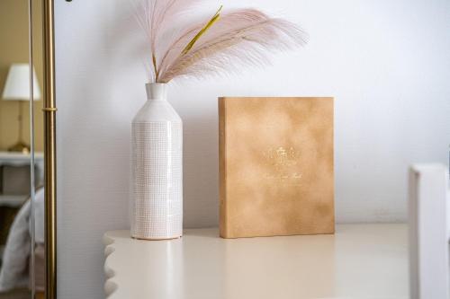 a white vase sitting on a table next to a book at Hotel Saint Paul in Noirmoutier-en-l'lle