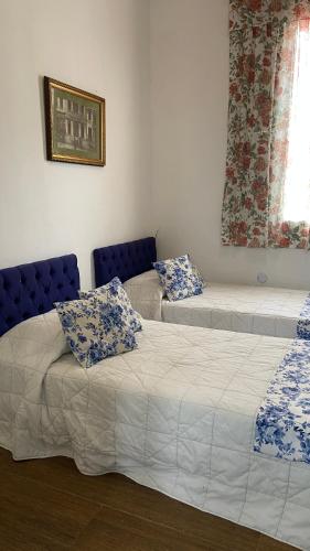 two beds in a room with blue chairs and a window at Mara Palace Hotel in Vassouras