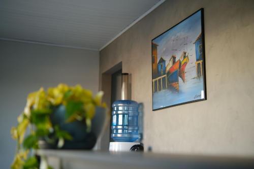 a vase with a plant and a picture on a wall at Estação da XV in Telêmaco Borba